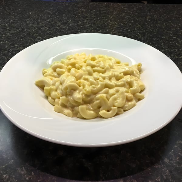 Creamy macaroni and cheese in a white bowl on a dark speckled counter at Sea Cliff Bagel Cafe.