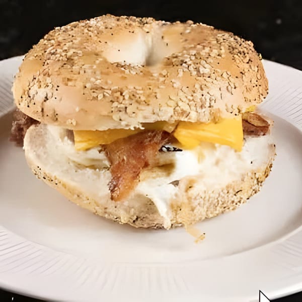 Everything bagel with bacon, egg, and cheese on a white plate at Sea Cliff Bagel Cafe.